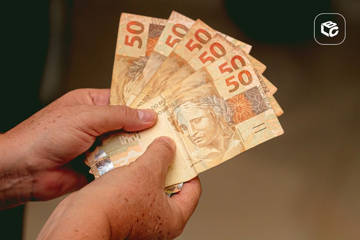 Mãos segurando notas de 50 reais, ilustrando o tempo de cessão de precatório.